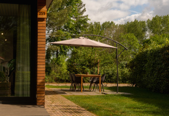 Zona pranzo all'aperto con ombrellone accanto a una baita in legno a Holiday Park Mölke, Paesi Bassi.