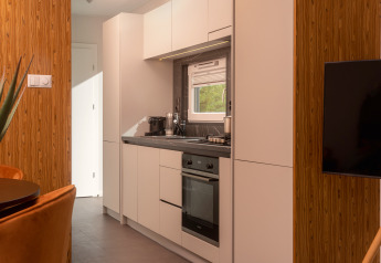 Cucina compatta moderna in una Tiny Cabin al Holiday Park Mölke nei Paesi Bassi, con mobili bianchi.