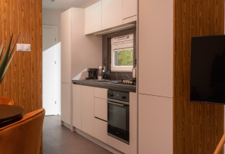 Moderne, kompakt køkken i en Tiny Cabin ved Holiday Park Mölke i Holland med hvide skabe og trævægge.