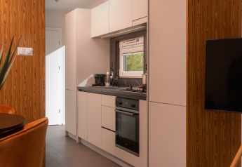 Moderne, kleine Küche in einer Tiny Cabin im Holiday Park Mölke, Niederlande, mit weißen Schränken.