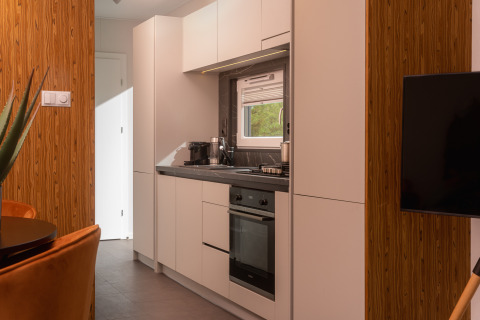 Moderne, kleine Küche in einer Tiny Cabin im Holiday Park Mölke, Niederlande, mit weißen Schränken.