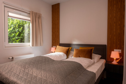 Slaapkamer in de Tiny Cabin van Holiday Park Mölke in Nederland, met tweepersoonsbed en sfeervolle verlichting.