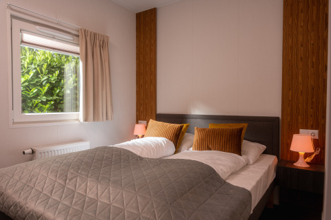 Schlafzimmer in der Tiny Cabin im Holiday Park Mölke, Niederlande, mit Doppelbett und gemütlicher Atmosphäre.