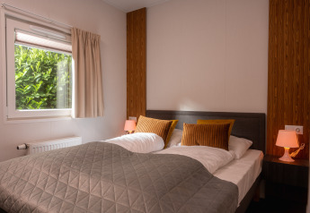 Schlafzimmer in der Tiny Cabin im Holiday Park Mölke, Niederlande, mit Doppelbett und gemütlicher Atmosphäre.