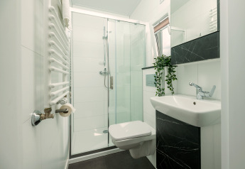 Bagno moderno con doccia in vetro, WC sospeso, lavandino e pianta in una Tiny Cabin a Holiday Park Mölke, Paesi Bassi.