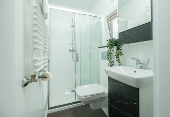 Baño moderno con ducha de vidrio, inodoro mural, lavabo y planta en Tiny Cabin de Holiday Park Mölke, Países Bajos.