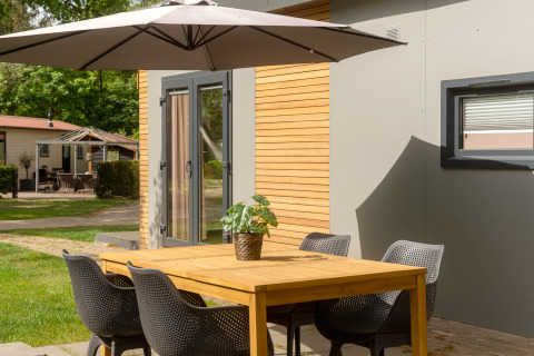 Buiten eettafel met stoelen en parasol bij Tiny Cabin in Holiday Park Mölke, Nederland, in de zomer.