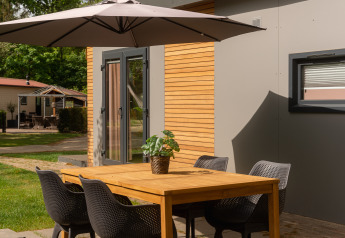 Udendørs spisebord og stole under parasol ved Tiny Cabin i Holiday Park Mölke i Holland om sommeren.