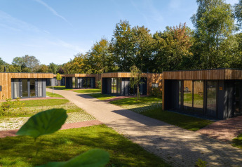 Moderne Happy Oak Lodge huisjes bij Holiday Park Mölke in Nederland, omgeven door bomen en groen.