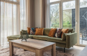 Gezellige woonkamer in Cosy Cabin bij Holiday Park Mölke, Nederland, met groene bank en houten tafel.