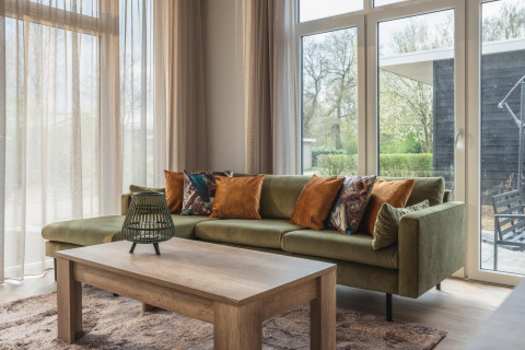 Gezellige woonkamer in Cosy Cabin bij Holiday Park Mölke, Nederland, met groene bank en houten tafel.