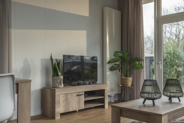 Woonkamer van Cosy Cabin bij Holiday Park Mölke, Nederland, met tv, planten en uitzicht op tuin.