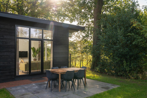 Zonnige ochtend aan de natuurhut met moderne buitentafel in Holiday Park Mölke, Nederland.