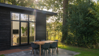 Sonniger Morgen an einer Naturhütte mit modernem Essbereich im Freien im Holiday Park Mölke, Niederlande.