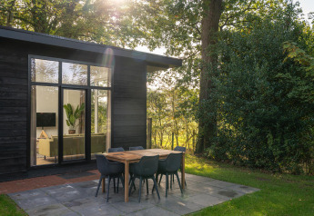 Sonniger Morgen an einer Naturhütte mit modernem Essbereich im Freien im Holiday Park Mölke, Niederlande.