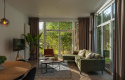 Modern living room in the Nature Cabin at Holiday Park Mölke, Netherlands, with large windows to nature.