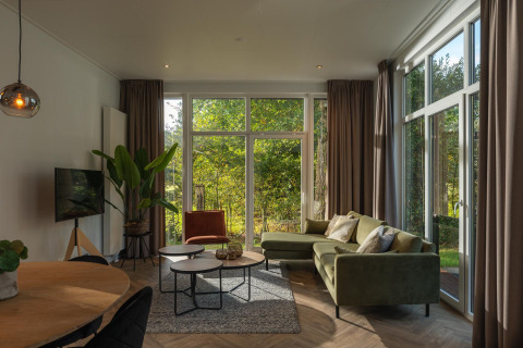 Modern living room in the Nature Cabin at Holiday Park Mölke, Netherlands, with large windows to nature.