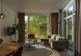 Modern living room in the Nature Cabin at Holiday Park Mölke, Netherlands, with large windows to nature.
