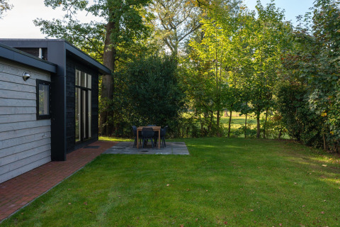 Udsigt til græsplæne og terrasse med spisebord ved Nature Cabin på Holiday Park Mölke, Holland.