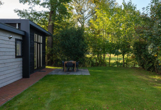 Grasveld en eethoek buiten bij Nature Cabin in Holiday Park Mölke, omringd door bomen in Nederland.