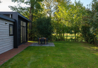 Grasveld en eethoek buiten bij Nature Cabin in Holiday Park Mölke, omringd door bomen in Nederland.