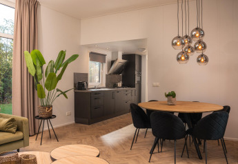 Soggiorno moderno e cucina della Nature Cabin al Holiday Park Mölke, con piante e tavolo da pranzo.