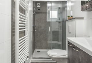 Baño moderno con ducha, inodoro suspendido y radiador toallero en Nature Cabin, Holiday Park Mölke.