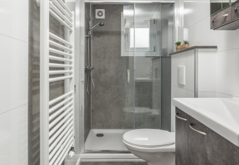 Salle de bain moderne avec douche, WC suspendu et sèche-serviettes à la Nature Cabin, Holiday Park Mölke.