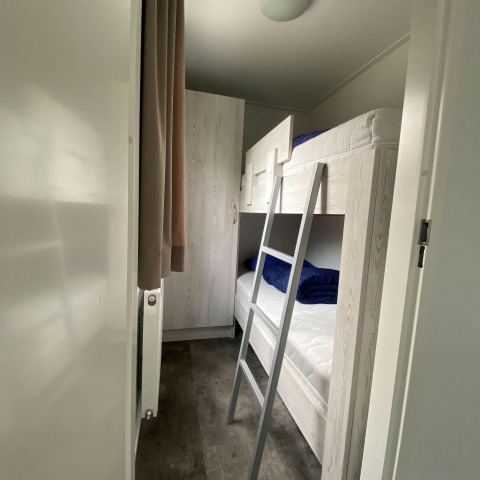 Et smalt værelse i Nature Cabin ved Holiday Park Mölke, Holland, med køjeseng og garderobeskab.