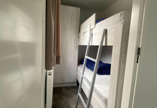 Narrow room in Nature Cabin at Holiday Park Mölke, Netherlands, featuring bunk beds and a wardrobe.