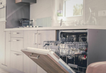 Open dishwasher in a modern kitchen of Cosy Cabin, Holiday Park Mölke in the Netherlands, sun shining.
