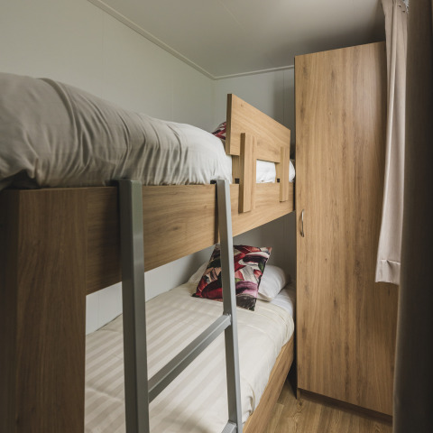 Habitación acogedora con litera y armario en Cosy Cabin, Holiday Park Mölke, Países Bajos.