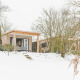 River Lodge at Holiday Park Mölke in the Netherlands, surrounded by snow, trees, and a wintry landscape.