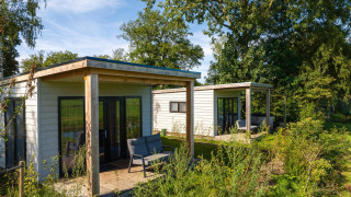 Deux lodges River Lodge modernes au Holiday Park Mölke, Pays-Bas, entourés de verdure et d’arbres.