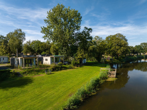 River Lodge chalets in Holiday Park Mölke, Nederland, gelegen aan rivier en omringd door groen.
