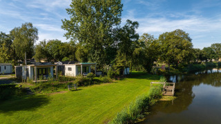 River Lodge chalets in Holiday Park Mölke, Nederland, gelegen aan rivier en omringd door groen.