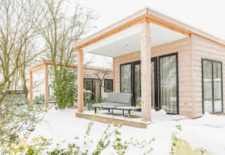 River Lodge im Holiday Park Mölke in den Niederlanden, umgeben von Schnee, mit gemütlicher Terrasse.