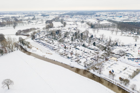 Luchtfoto van River Lodge bij Holiday Park Mölke in Nederland, omgeven door besneeuwd landschap en rivier.
