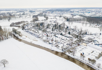 Luftfoto af River lodge ved Holiday Park Mölke i Holland, dækket af sne om vinteren nær en flod.