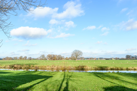 Grüne Wiese, Fluss und blauer Himmel naht River Lodge im Holiday Park Mölke, Niederlande.