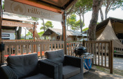 Terraza exterior en Villatent Outback con sillones de mimbre, barbacoa y tiendas safari de lujo alrededor.