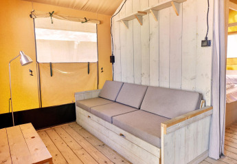 Innenaufnahme eines Villatent Outback Safarizelts mit Holzsofa, Tisch und minimalistischem Dekor.