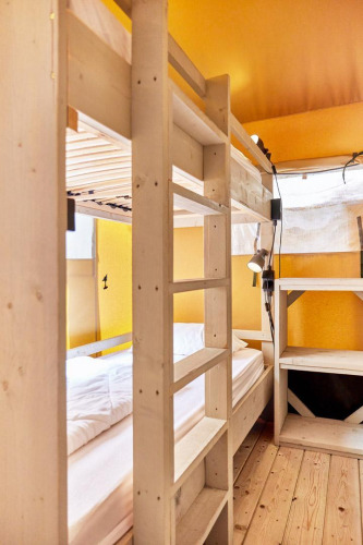 Interior view of a safari tent with bunk beds and wooden shelves at Villatent Outback.