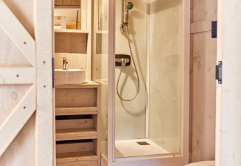 Modern bathroom in a safari tent with shower cabin, toilet, sink and wooden floor at Villatent Outback.