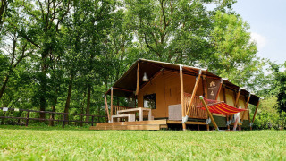 Tenda safari Villatent Nomad con veranda e amaca al Recreatiepark de Lucht nei Paesi Bassi, circondata da alberi.
