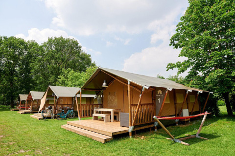 Tiendas safari Villatent Nomad en Recreatiepark de Lucht, Países Bajos, rodeadas de césped y árboles verdes.