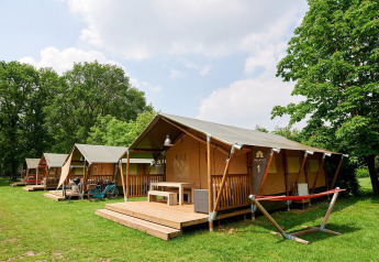 Safari-telte ved Villatent Nomad på Recreatiepark de Lucht i Holland, omgivet af grønne træer og græs.
