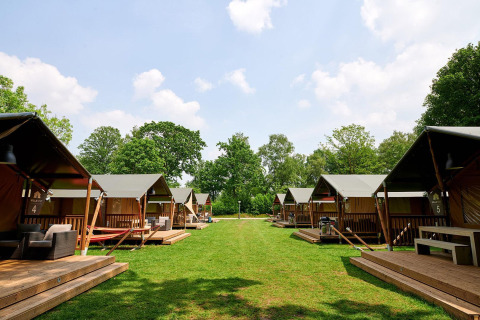 Safari-Zelte im Recreatiepark de Lucht, Niederlande, auf grünem Rasen unter blauem Himmel im Sommer.