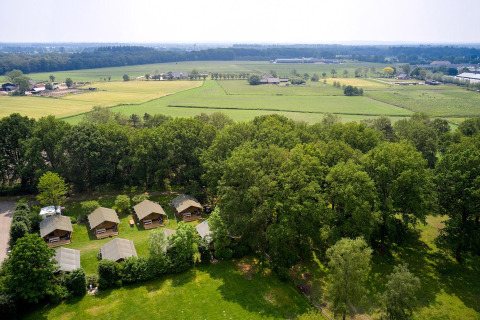 Vista aérea de las tiendas safari Villatent Nomad en Recreatiepark de Lucht, rodeadas de campo verde.