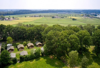 Vista aérea de las tiendas safari Villatent Nomad en Recreatiepark de Lucht, rodeadas de campo verde.